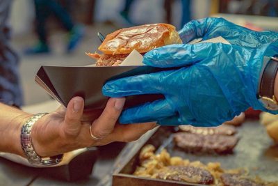 guanto azzurro da cucina che serve un hamburger